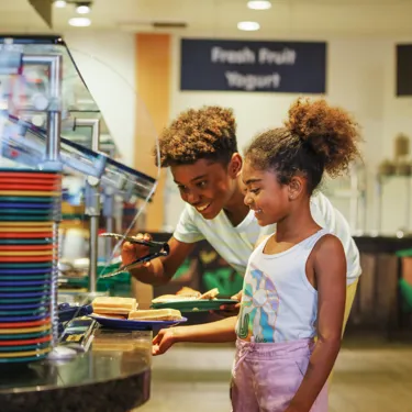 Two Kids Grab Food from the Kids-Sized Buffet Line