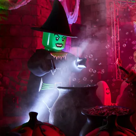 Witch Minifigure Costume Character hovers above cauldron at Brick-or-Treat