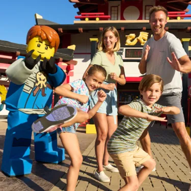 Family posing as Ninjas with Jay in front of LEGO Ninjago: The Ride